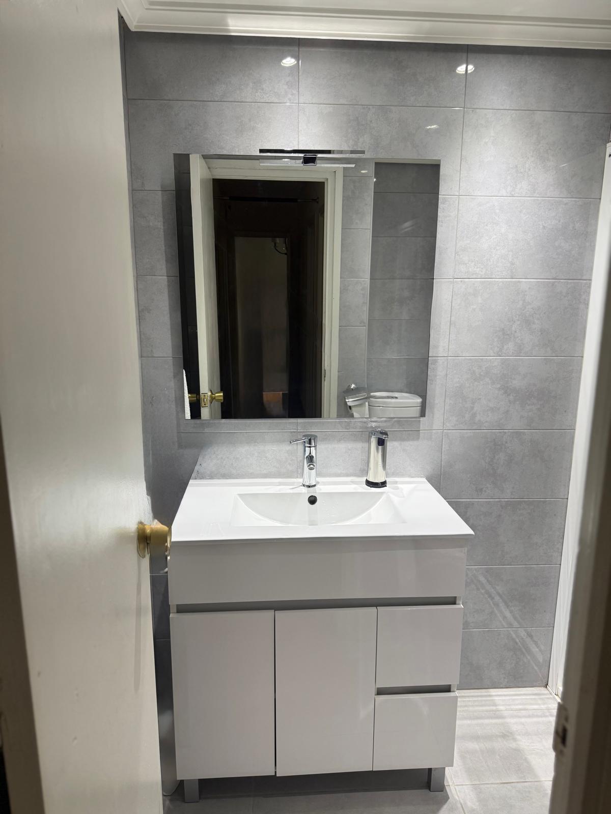 Reforma de baño con mampara de cristal, perfilería cromada y ventana de aluminio en Madrid