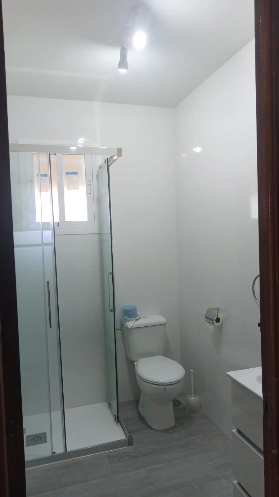 Reforma de baño con mampara de cristal corredera y suelo cerámico gris en Madrid