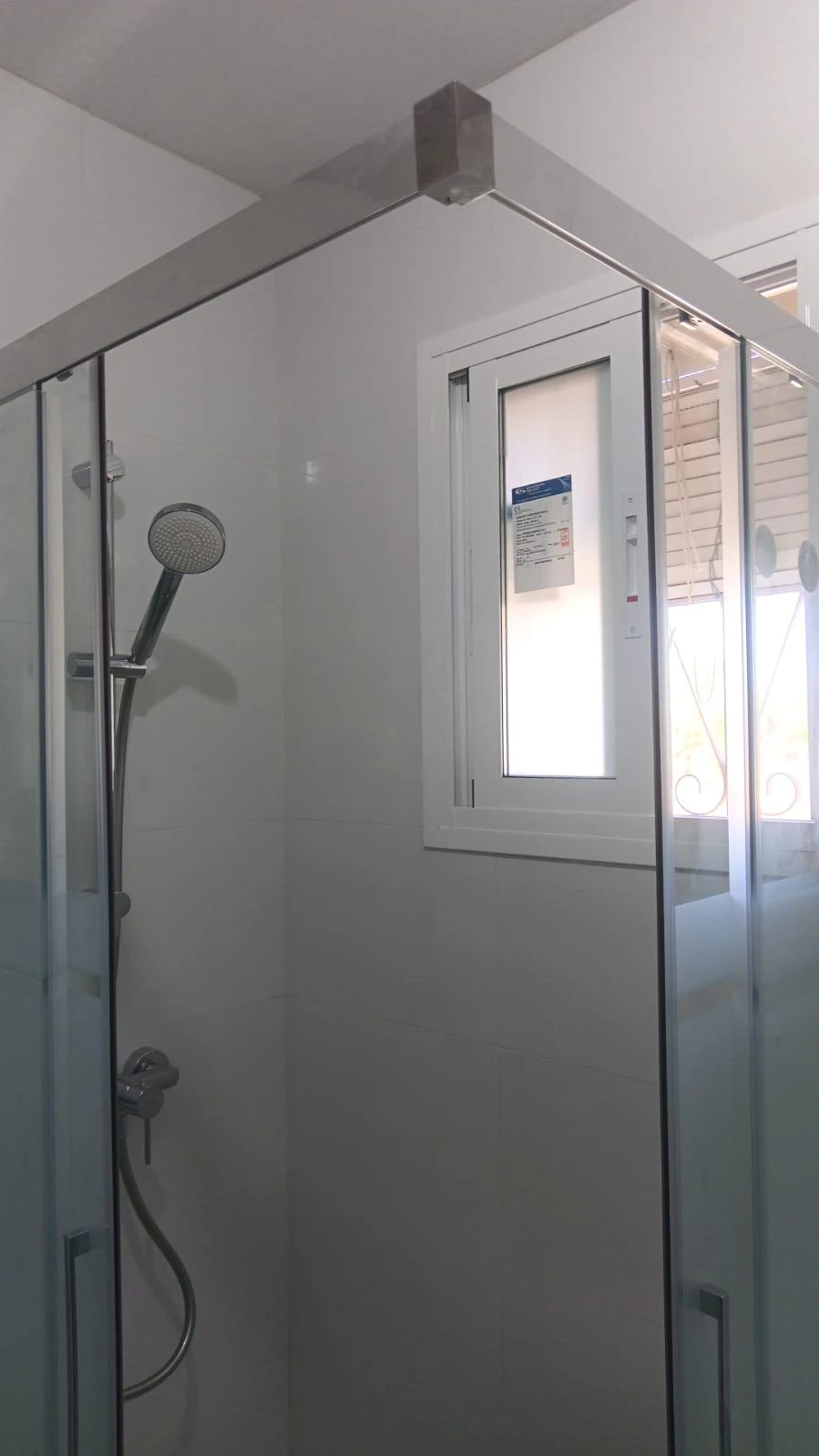Reforma de baño con mampara de cristal, perfilería cromada y ventana de aluminio en Madrid