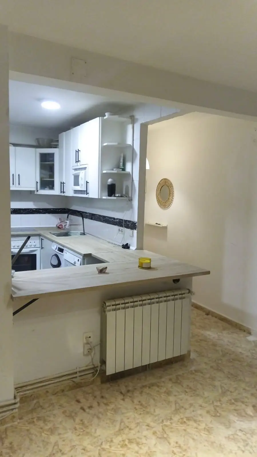 Reforma de cocina abierta con barra de madera clara y mobiliario blanco en Madrid