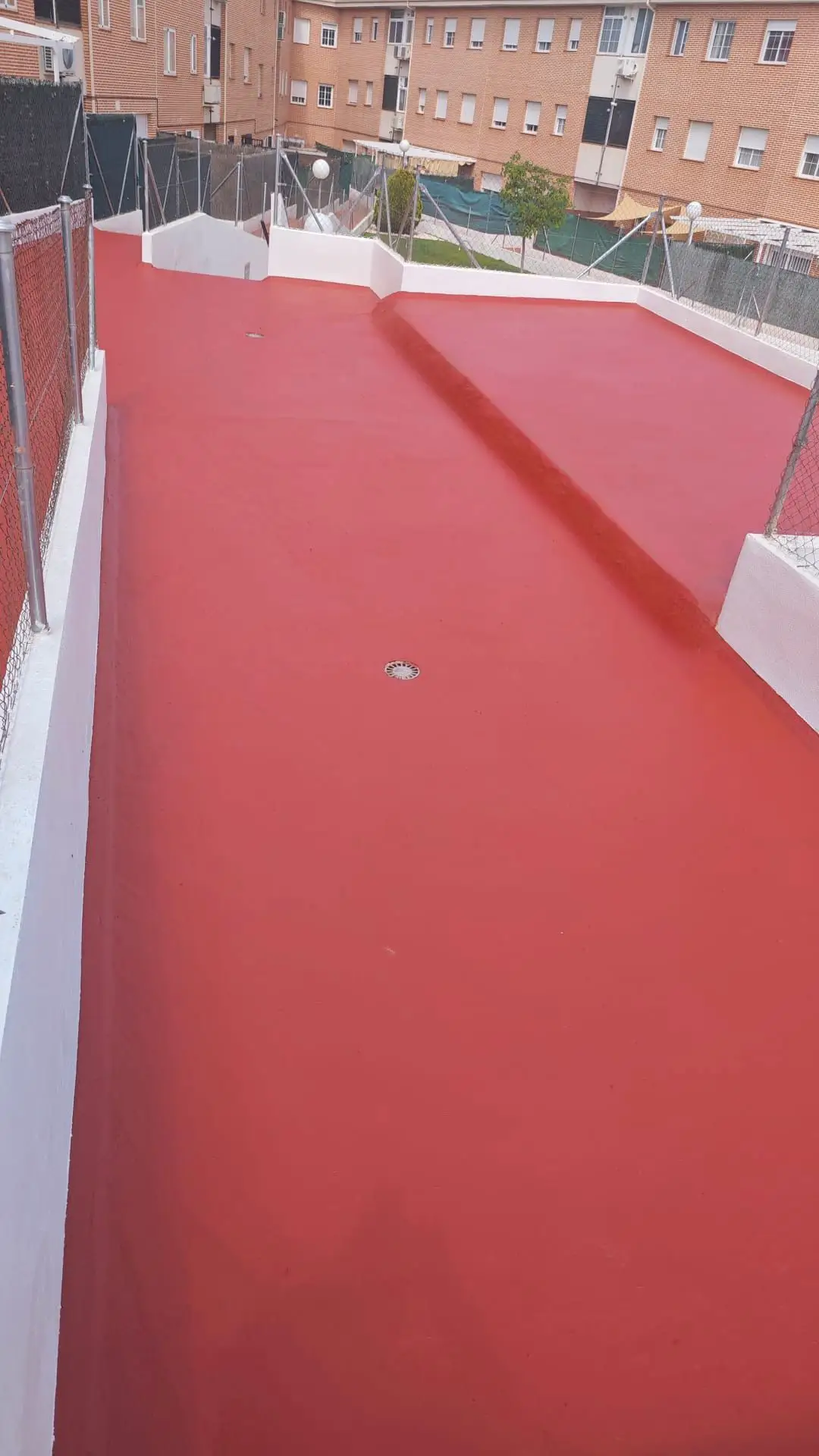Rehabilitación de cubierta con aplicación de pintura impermeabilizante roja y muretes blancos en Madrid